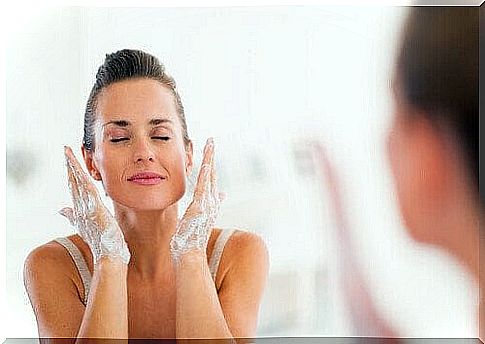 Woman cleanses her face in front of the mirror