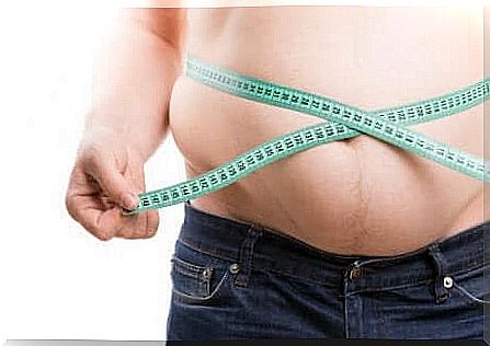 Overweight man measures the circumference of the abdomen with a tape measure.