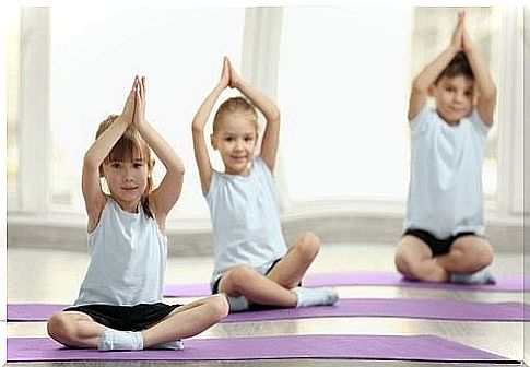 Children with arms up practicing yoga